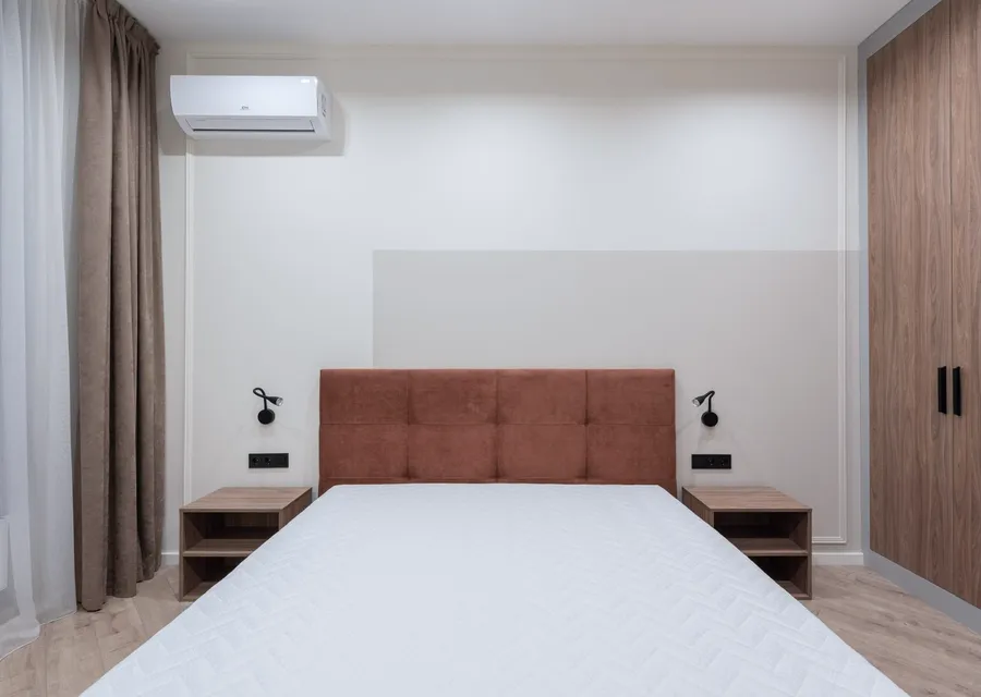 Bedroom with a wall-mounted air-conditioning unit above the bed