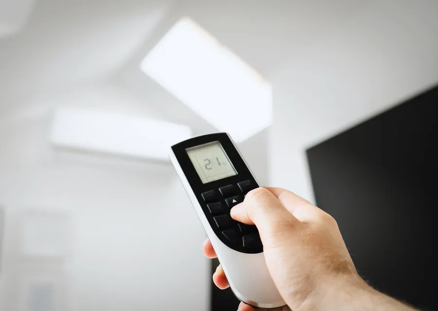 A hand pointing a remote control at a wall unit
