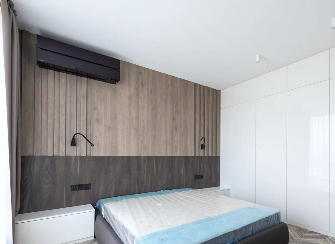 A wall-mounted air-conditioning unit in a warmly lit bedroom